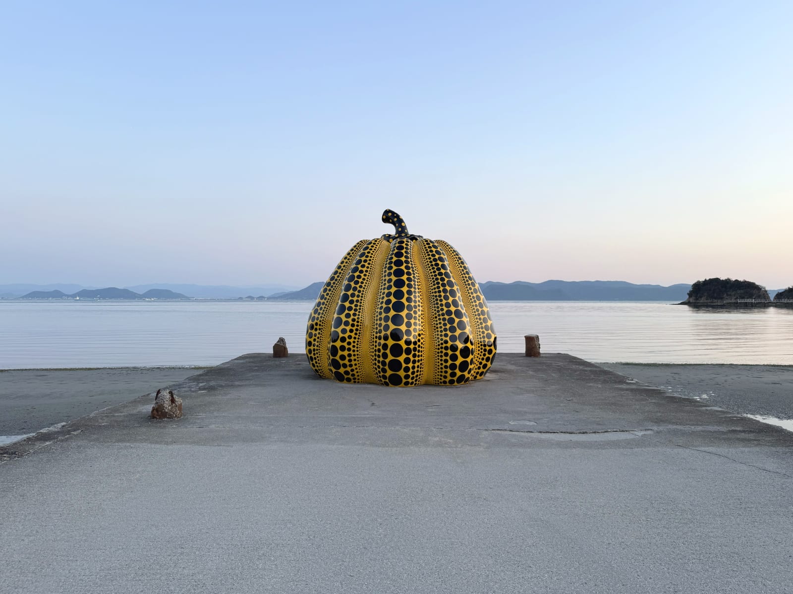Evening view of Yayoi Kusama's iconic "Yellow Pumpkin" on Naoshima Island in front of the Benesse House. © OSME Fine Art 2025