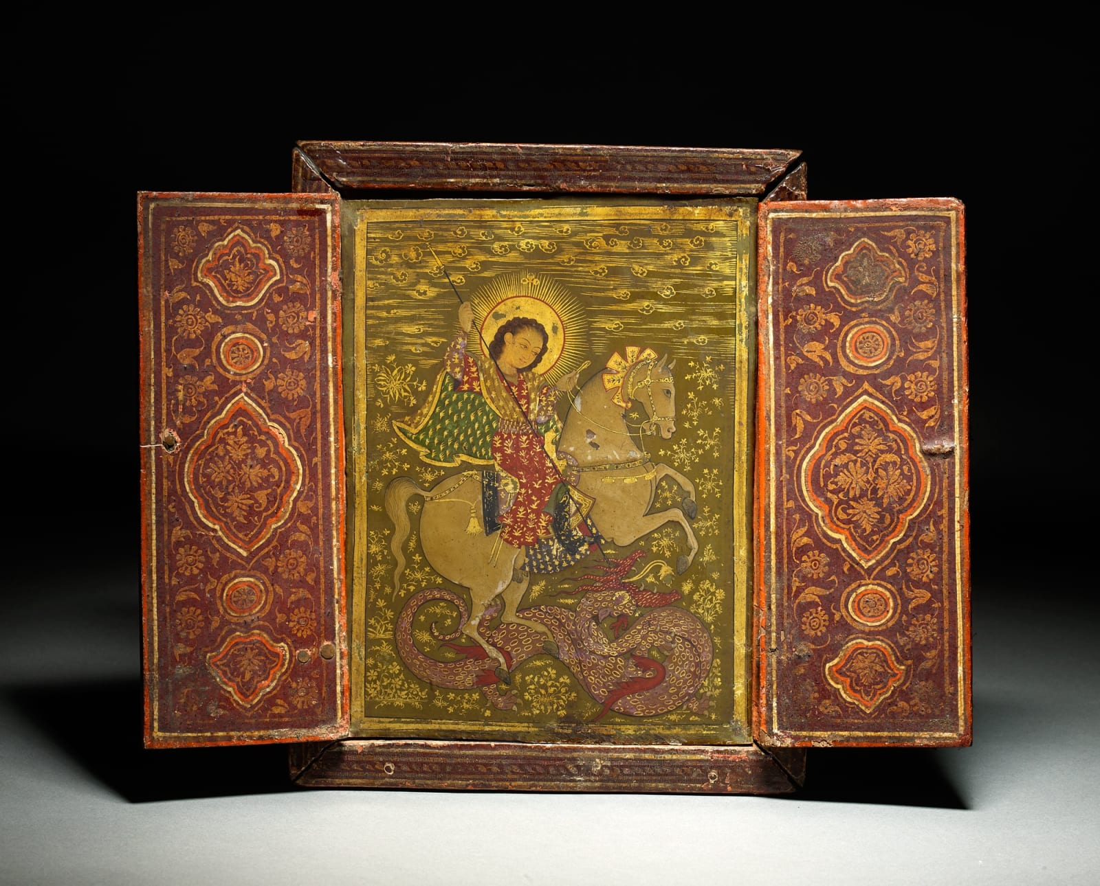 A very rare Votive Panel of St George & the Dragon inside a painted wooden triptych, By an Indian or Indian trained artist for the Ethiopian market, circa 1680-1700