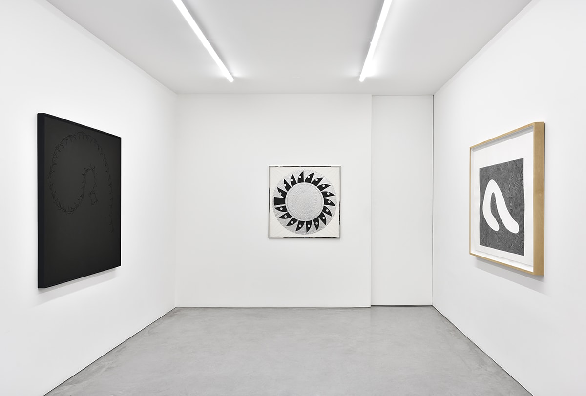 Three framed abstract works on three separate walls.