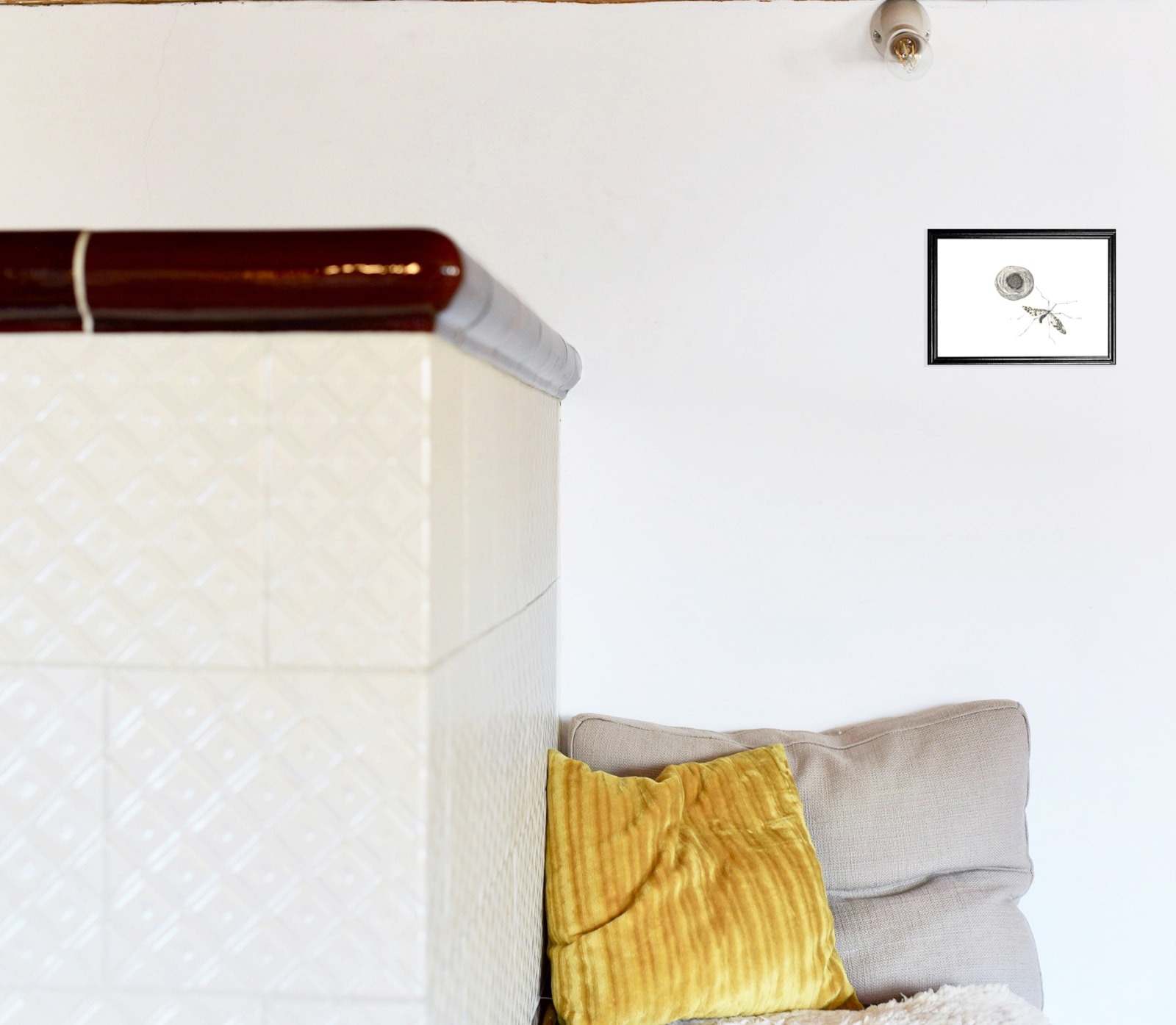 anna-stemmer-dworak-image is a mockup of a framed drawing of a fly and a birds nest hanging over a seat with pillows and an old big white tile oven