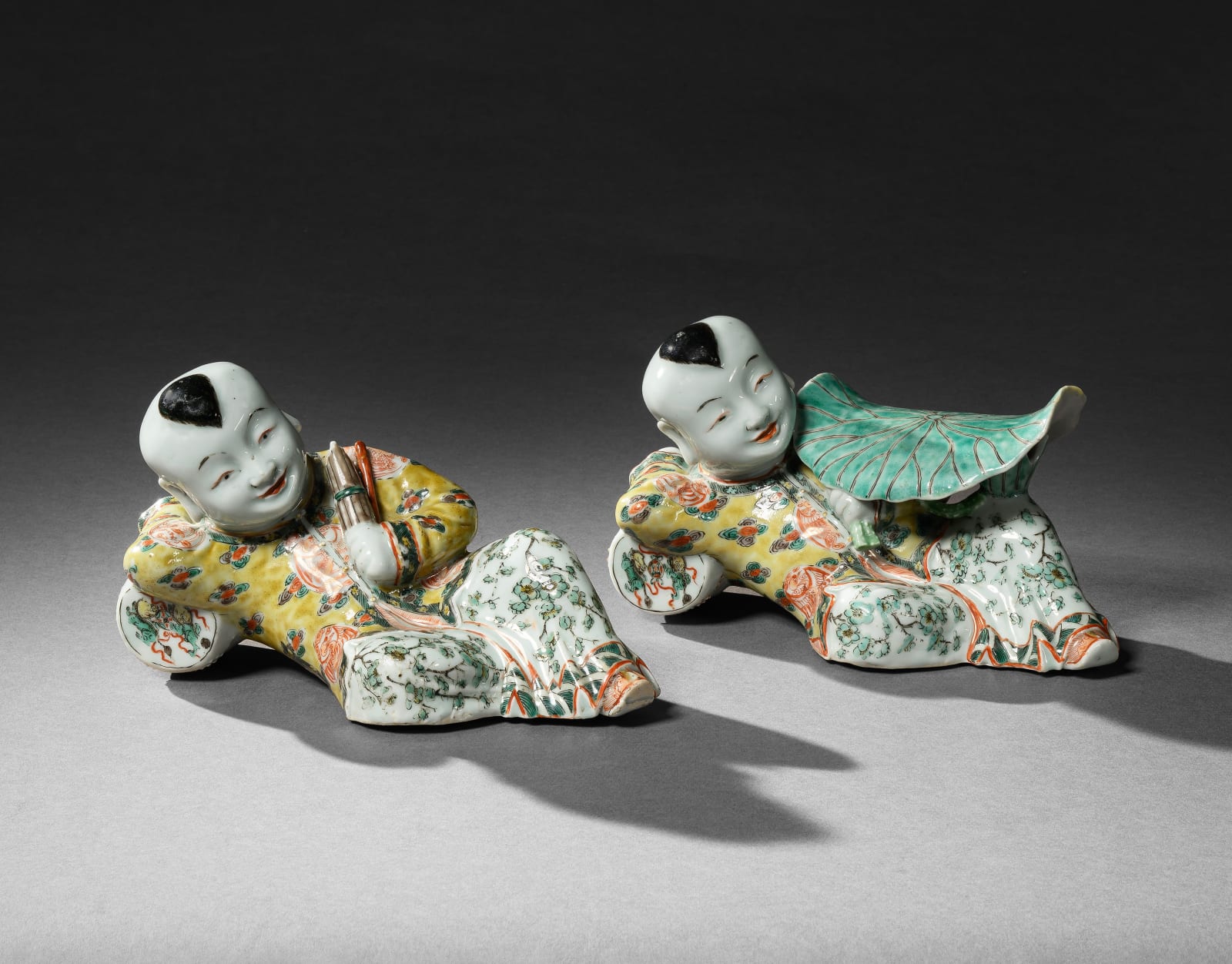A PAIR OF FAMILLE VERTE FIGURES OF RECUMBENT BOYS, KANGXI PERIOD (1662 - 1722)