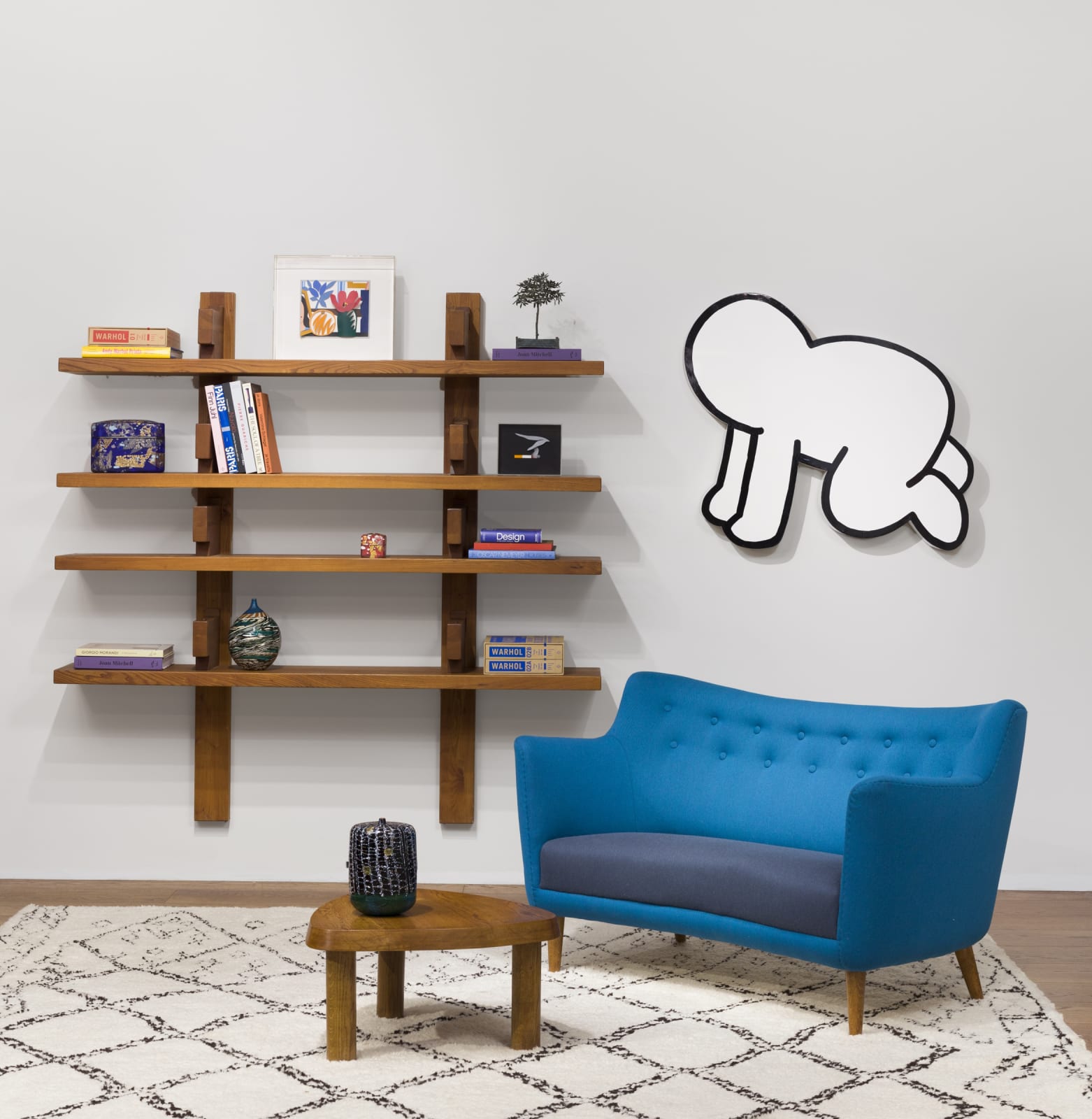 Installation shot showing Pierre Chapo bookcase, decorated with various books and small art as well as a Keith Haring work and other elements of art and design