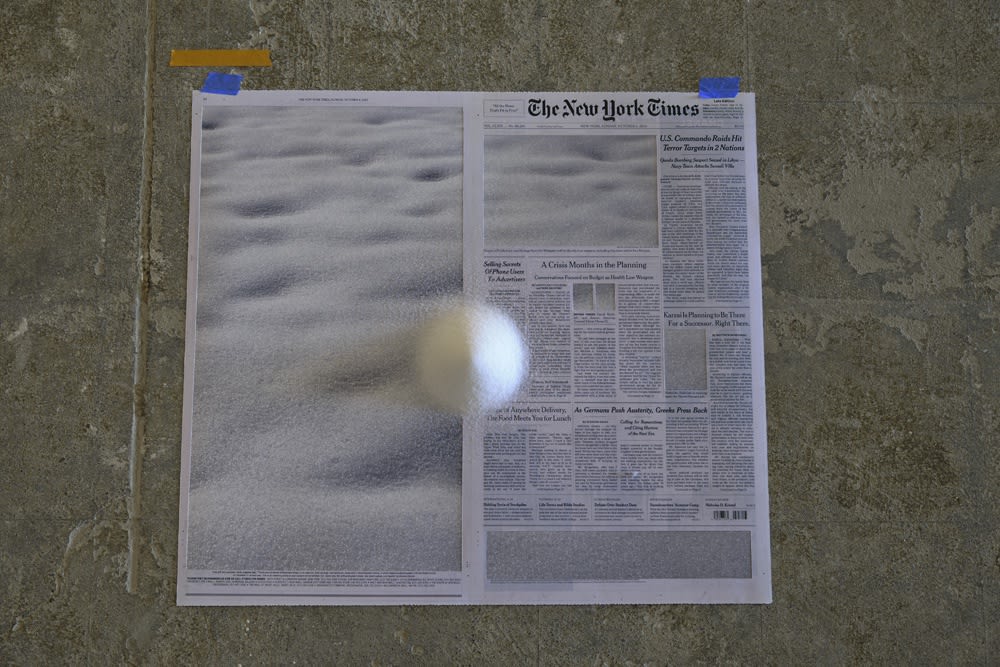 Installation view with newspapers on floor and rocks
