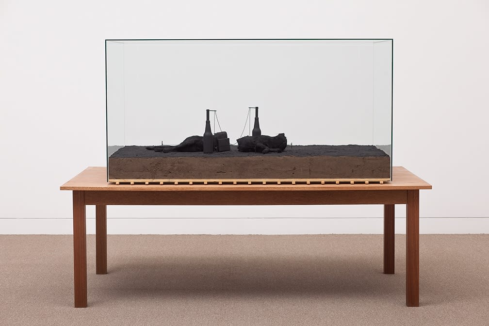 Image of Mark Manders sculpture with dark table and glass case