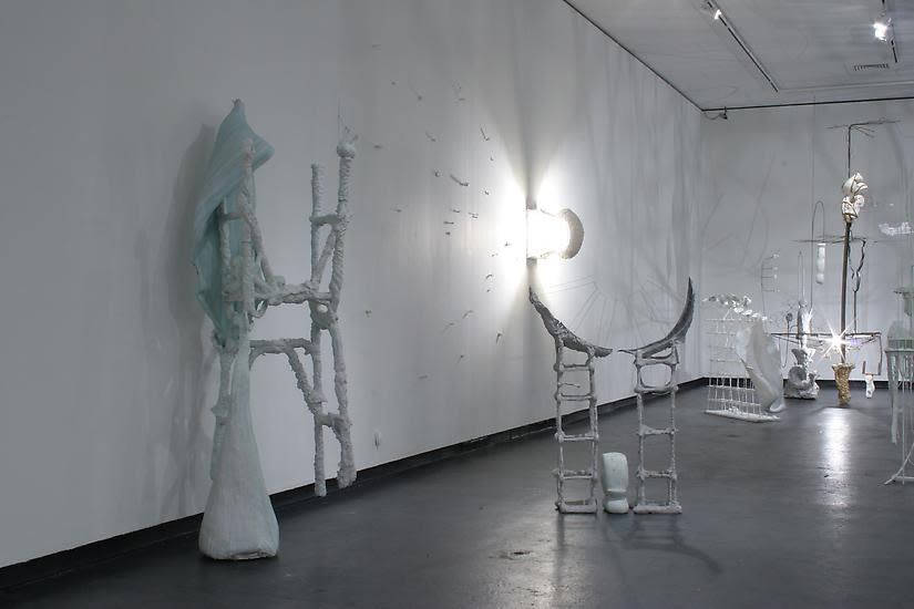 image of installation image of multiple Charles Long white sculptures, dim lighting and shadows