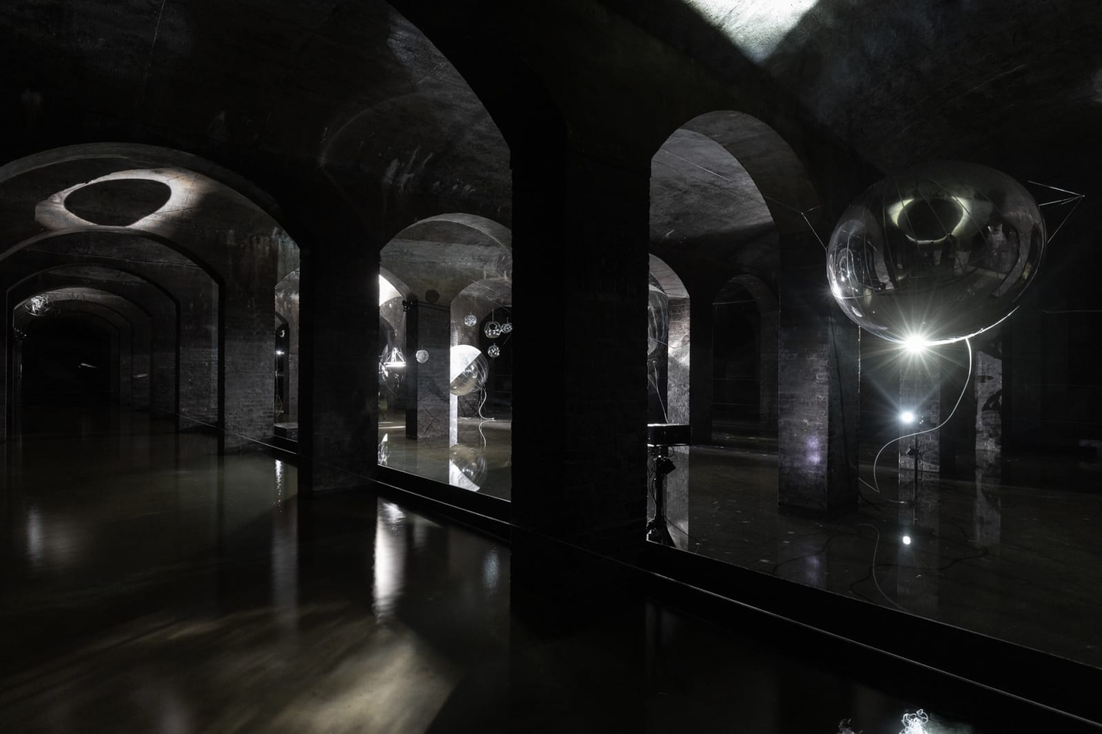 image of Saraceno sculptures hanging in dark room over water