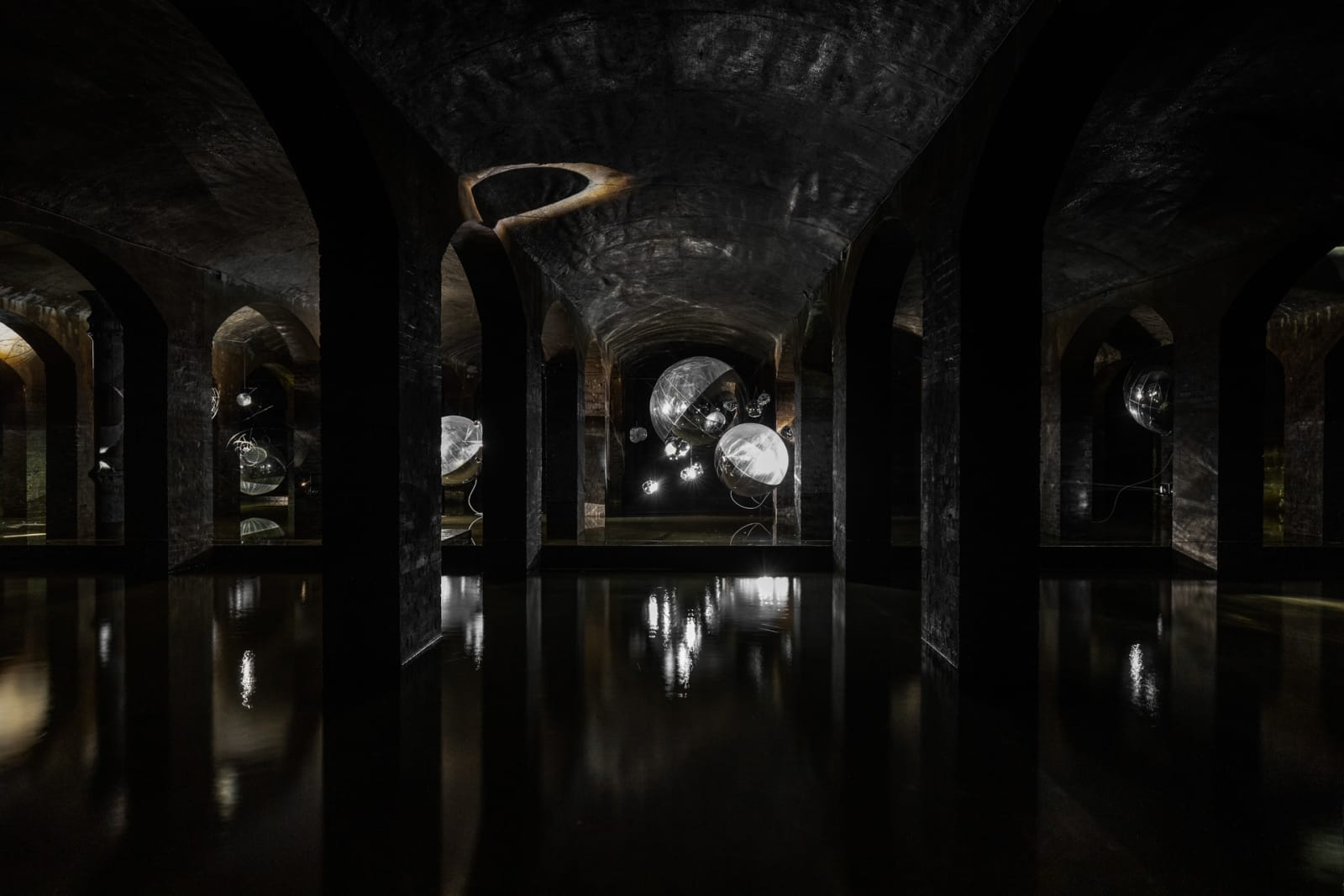 image of Saraceno sculptures hanging in dark room over water