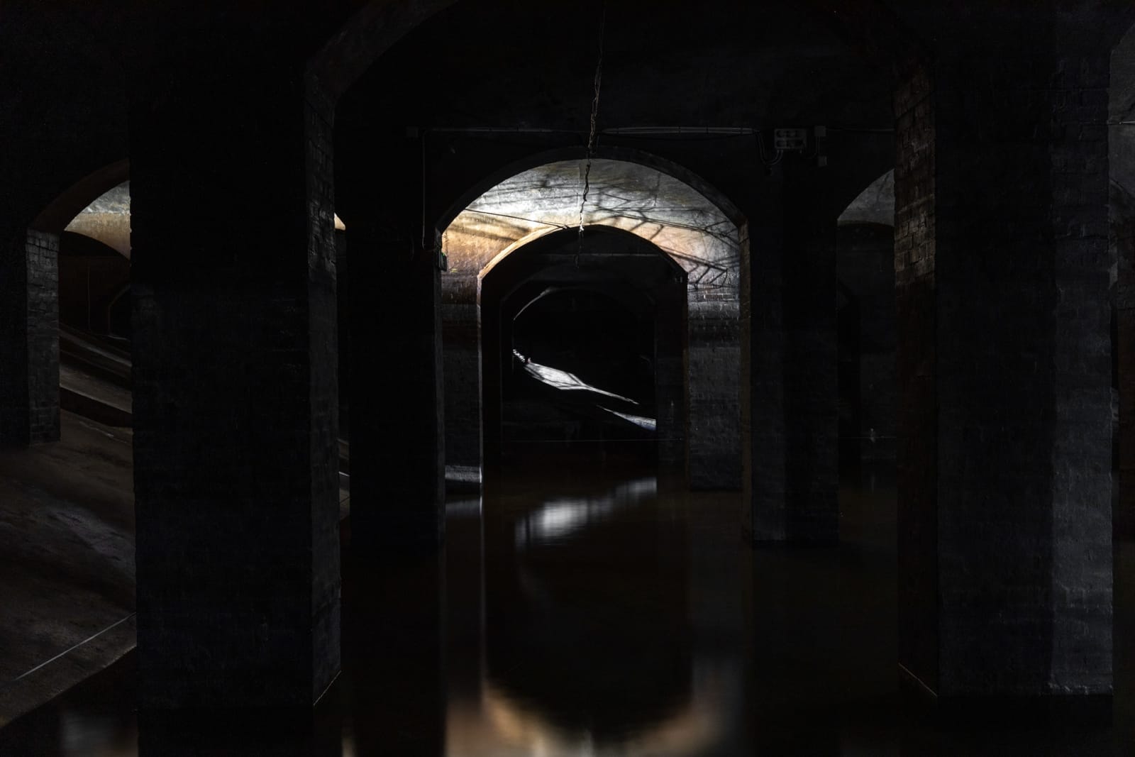 image of Saraceno sculptures hanging in dark room over water