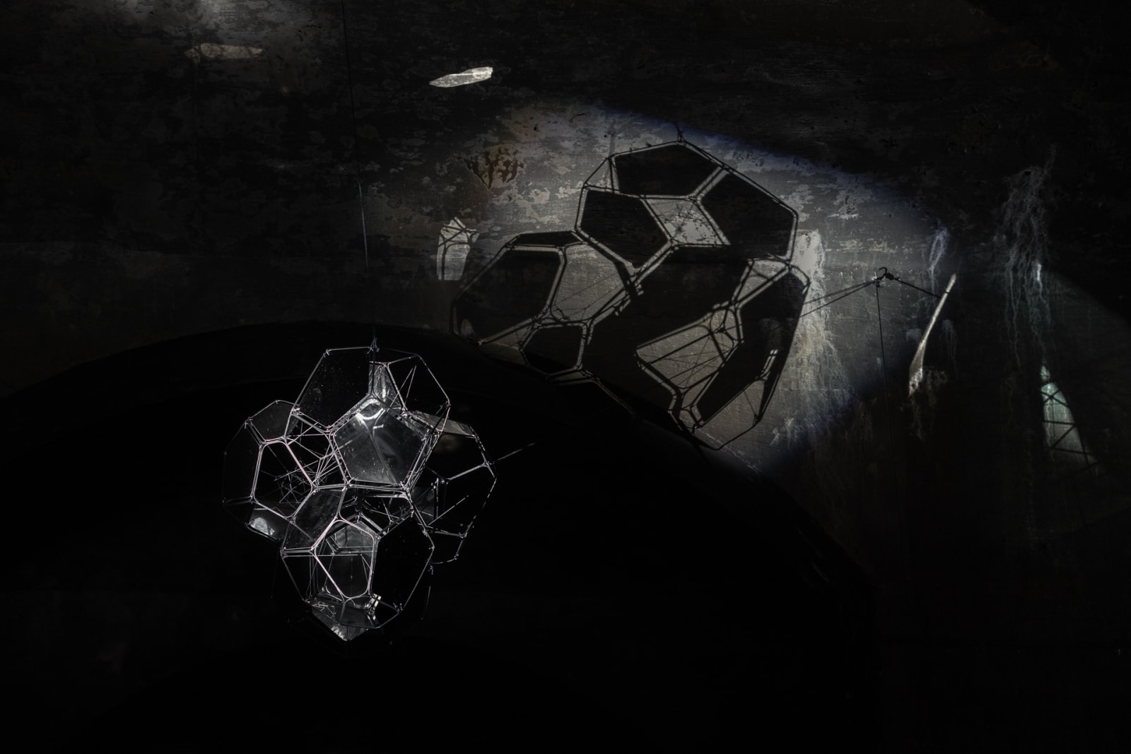 image of Saraceno sculptures hanging in dark room over water