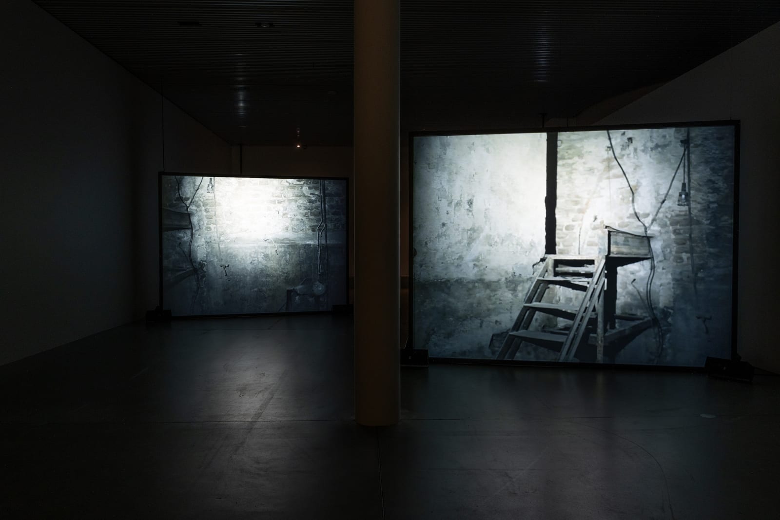 Susan Philipsz's film still image, two channel projection of concrete building facades in dark room