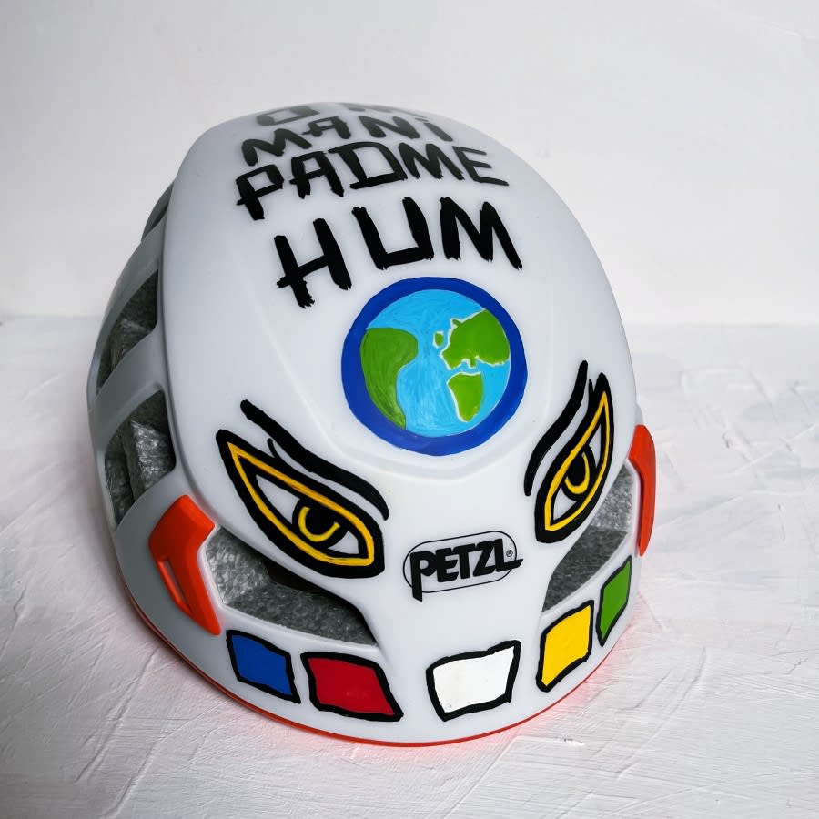 the custom painted lid features Buddhist mantra, eyes and prayer flags and a planet earth