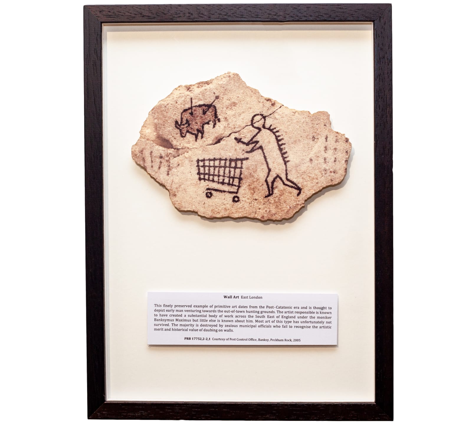 Banksy, Peckham Rock, Wooden postcard, sepia tone image of an imitation cave man drawing featuring a shopping trolley
