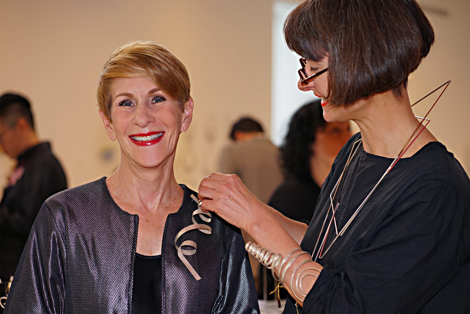 Fig. 2. Ute Decker adjusts her Calligraphy brooch in recycled silver for Bonnie Levine, former chair of the board of...