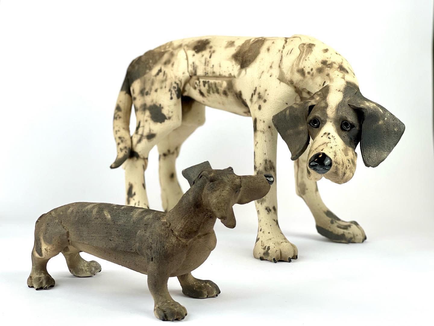 Ceramic sculpture of two individual dogs looking at each other by Virginia Dowe Edwards