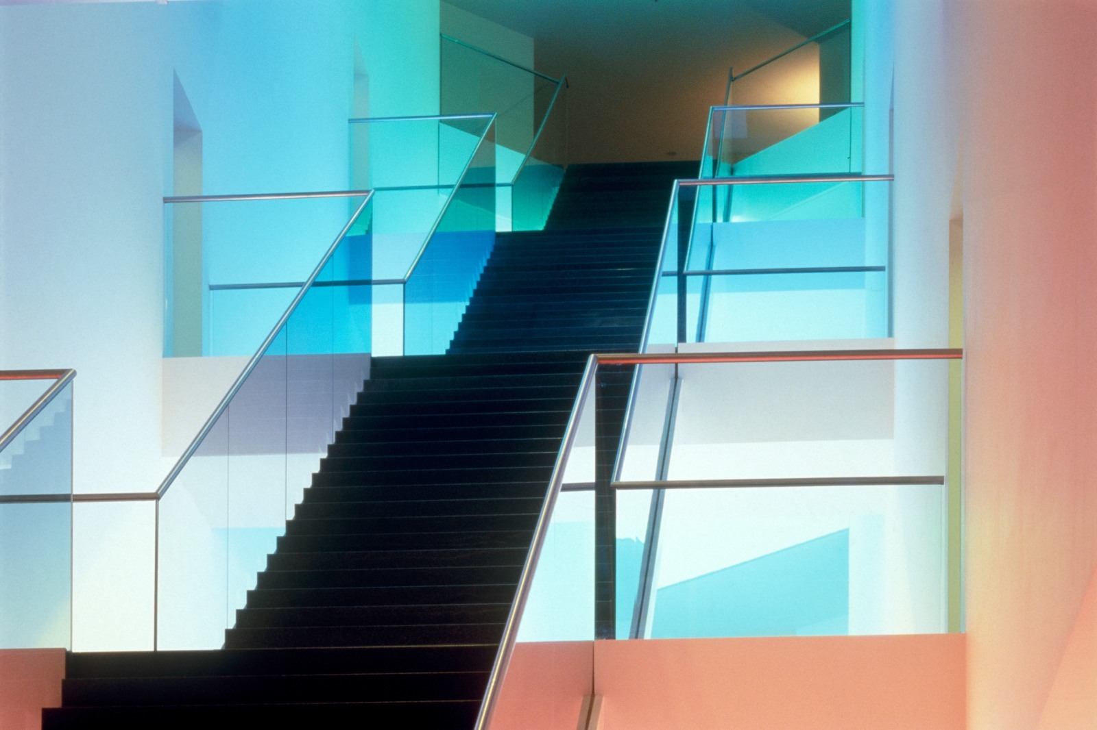 A light installation at the former Hypo-Bank in Munich using the building's diagonal staircase. Each step holds a pink, yellow, blue, or green lamp.