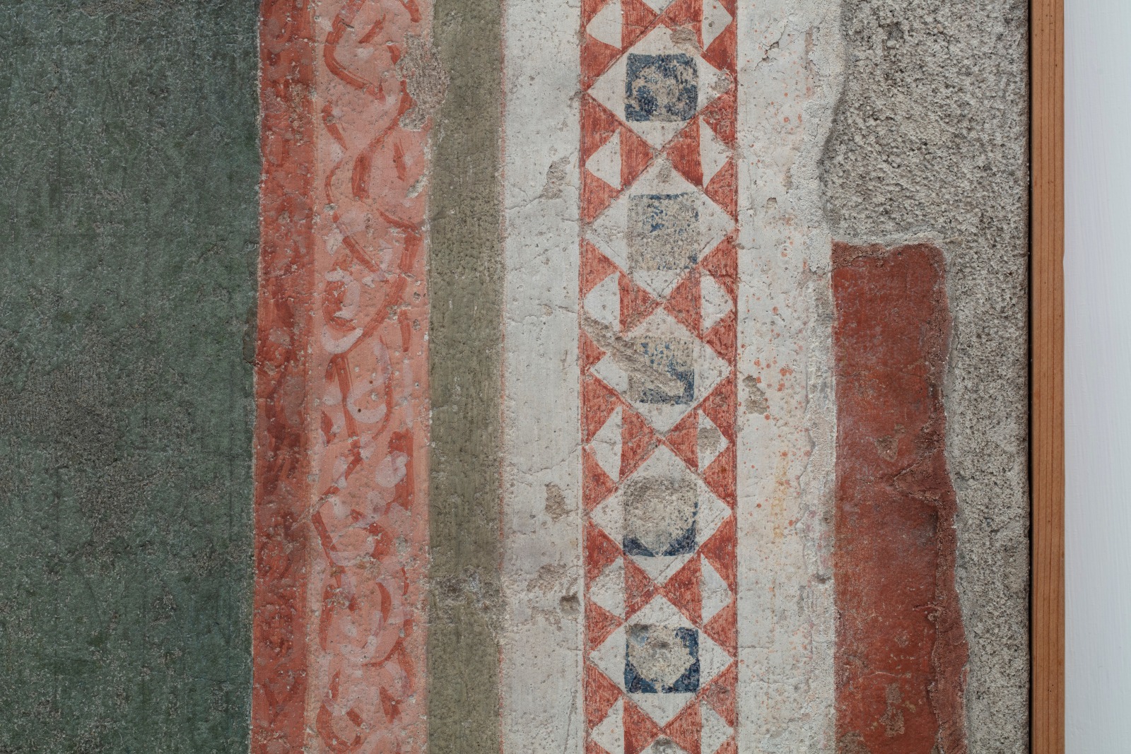 Detail of a ripped fresco of the Virgin Mary in Majesty holding Jesus Christ. This detail shows the patterned edge of the architecture framing the two figures.