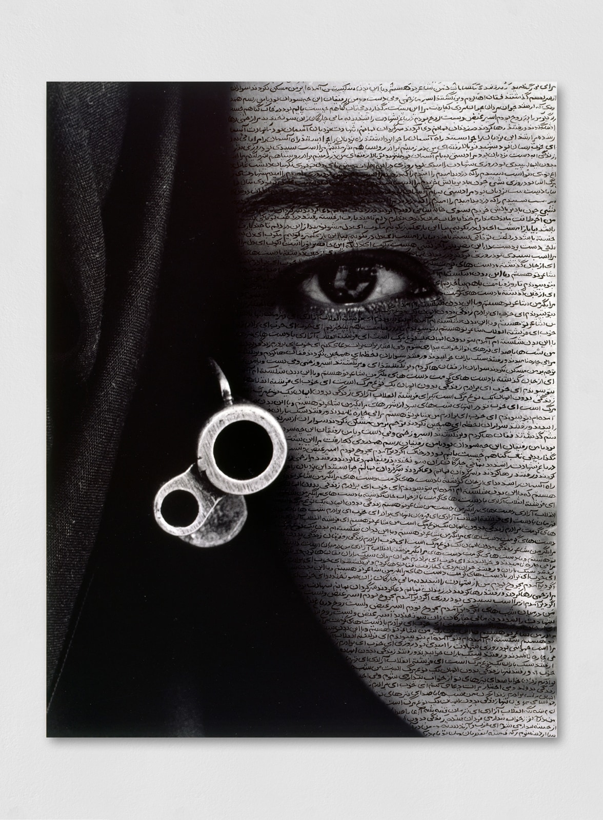 A Ink on silver gelatin print of a woman’s face alongside the barrel of a gun and inscribed across the surface were the words from a poem written by Tahereh Saffarzadeh.