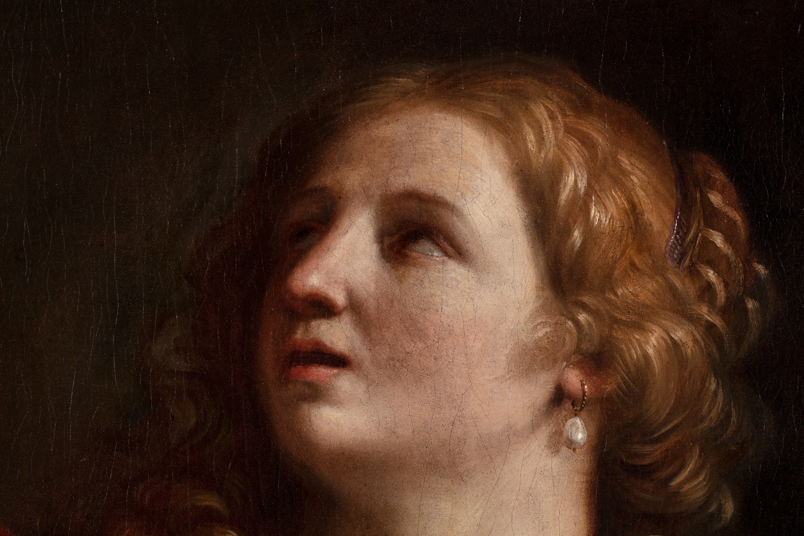 Detail of a painting depicting the face of a woman with long wavy blond hair.