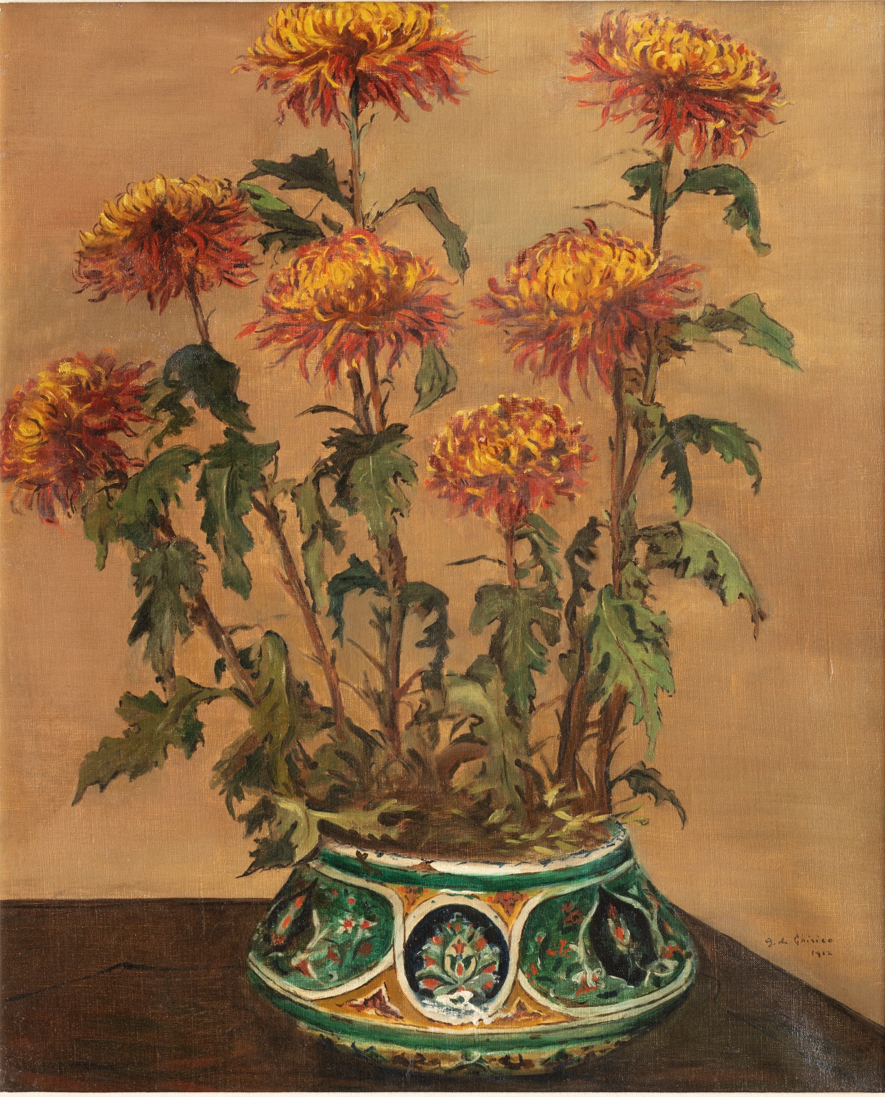 Oil painting of yellow and orange chrysanthemums with green leaves against a beige background in a green and yellow decorative vase positioned on a wooden surface.