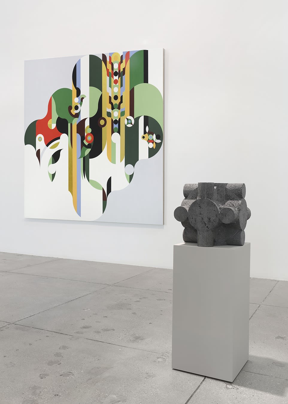 A small stone sculpture in front of an abstract, geometric painting. 