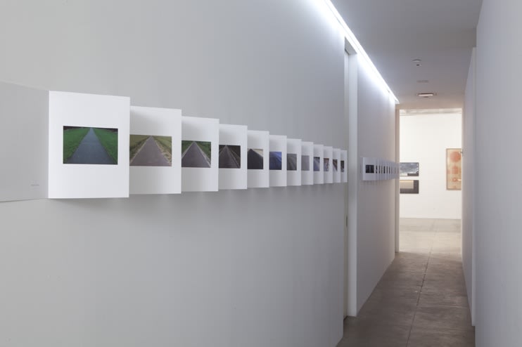 Multiple photographs line the left side of a hallway in a book-style format. 