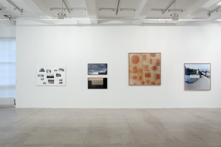 Four photographic works are displayed on a white wall. 