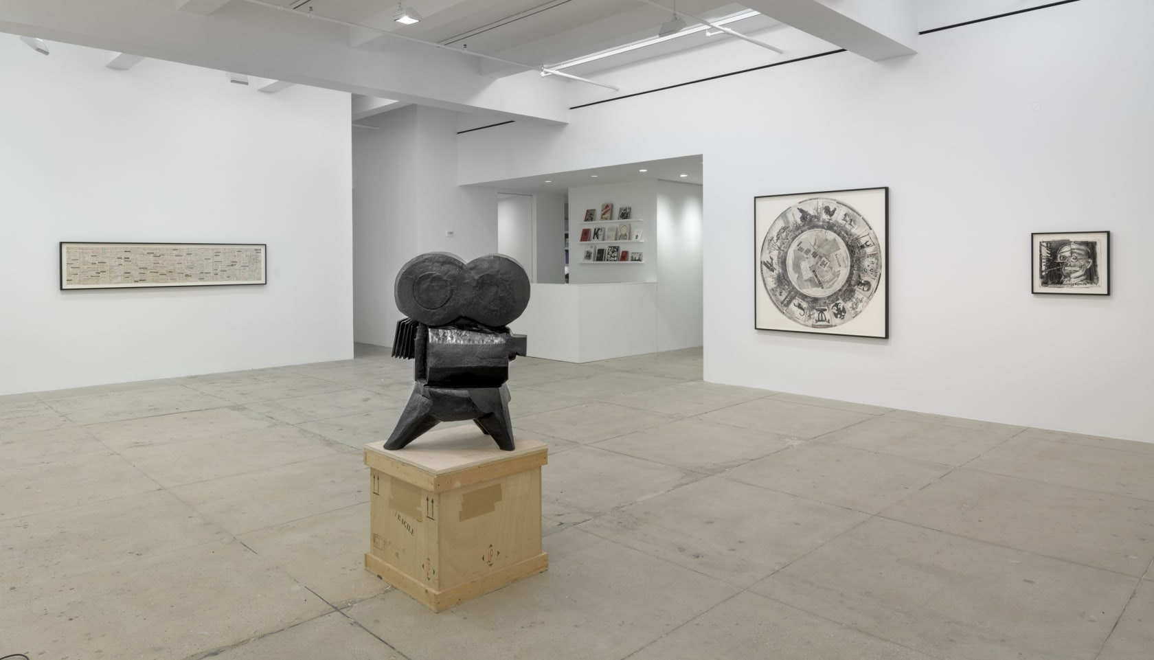 A copper sculpture of an old Hollywood camera stands on top of a wooden crate. Three graphite drawings fill the walls in the background. 