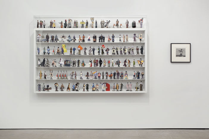 Gallery view of one framed black and white print and a large six-tiered shelf with numerous small figurines.