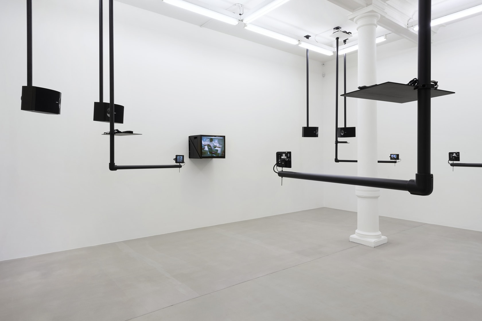 Black pipes attached to the ceiling at right angles hold various sized monitors.