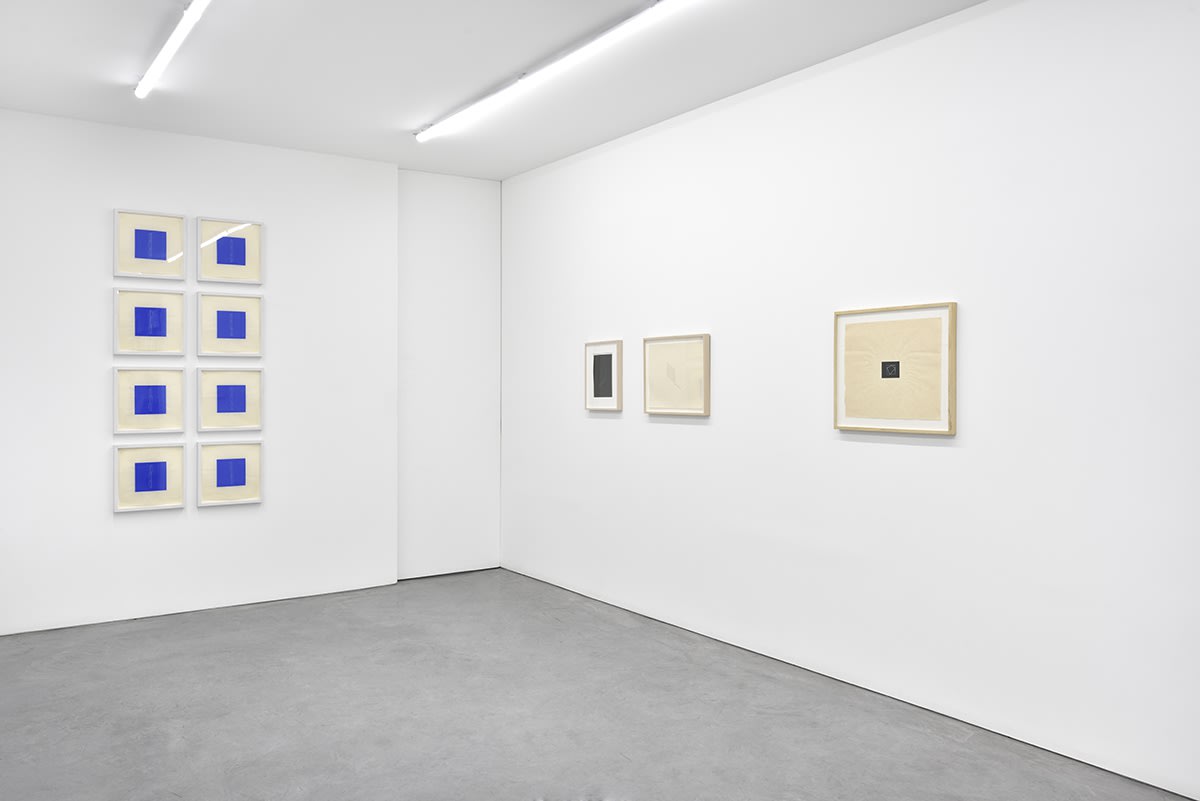 11 framed artworks hang in the gallery. To the left, they form a grid of blue squares.