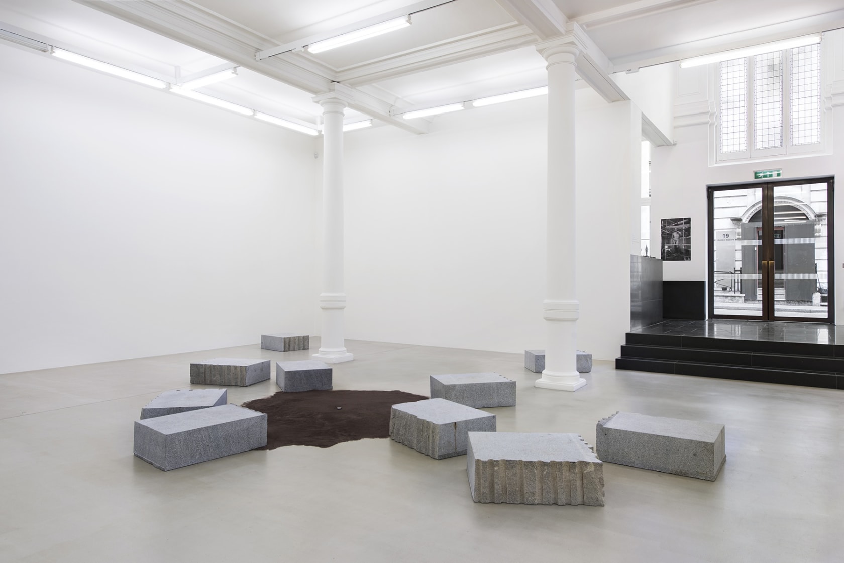 Installation of carved stone blocks around brown suede rug.
