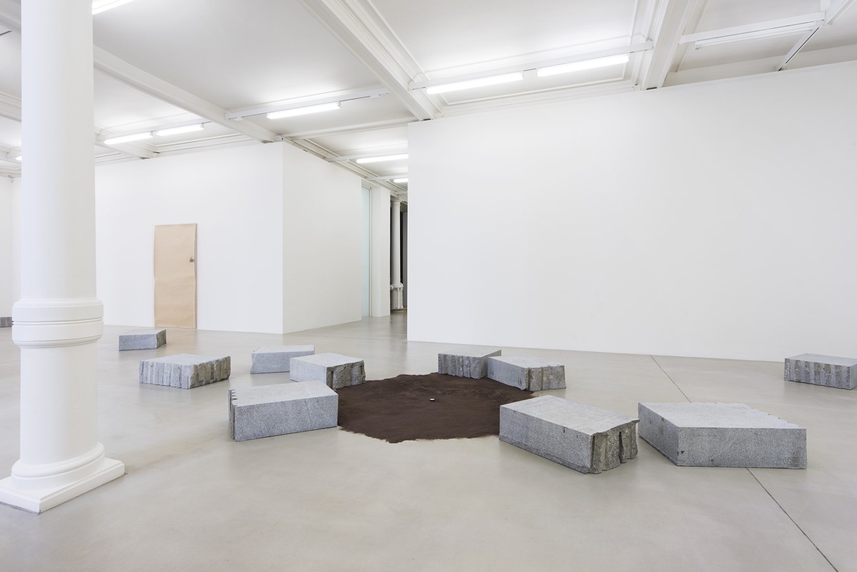 Installation of carved stone blocks around brown suede rug.