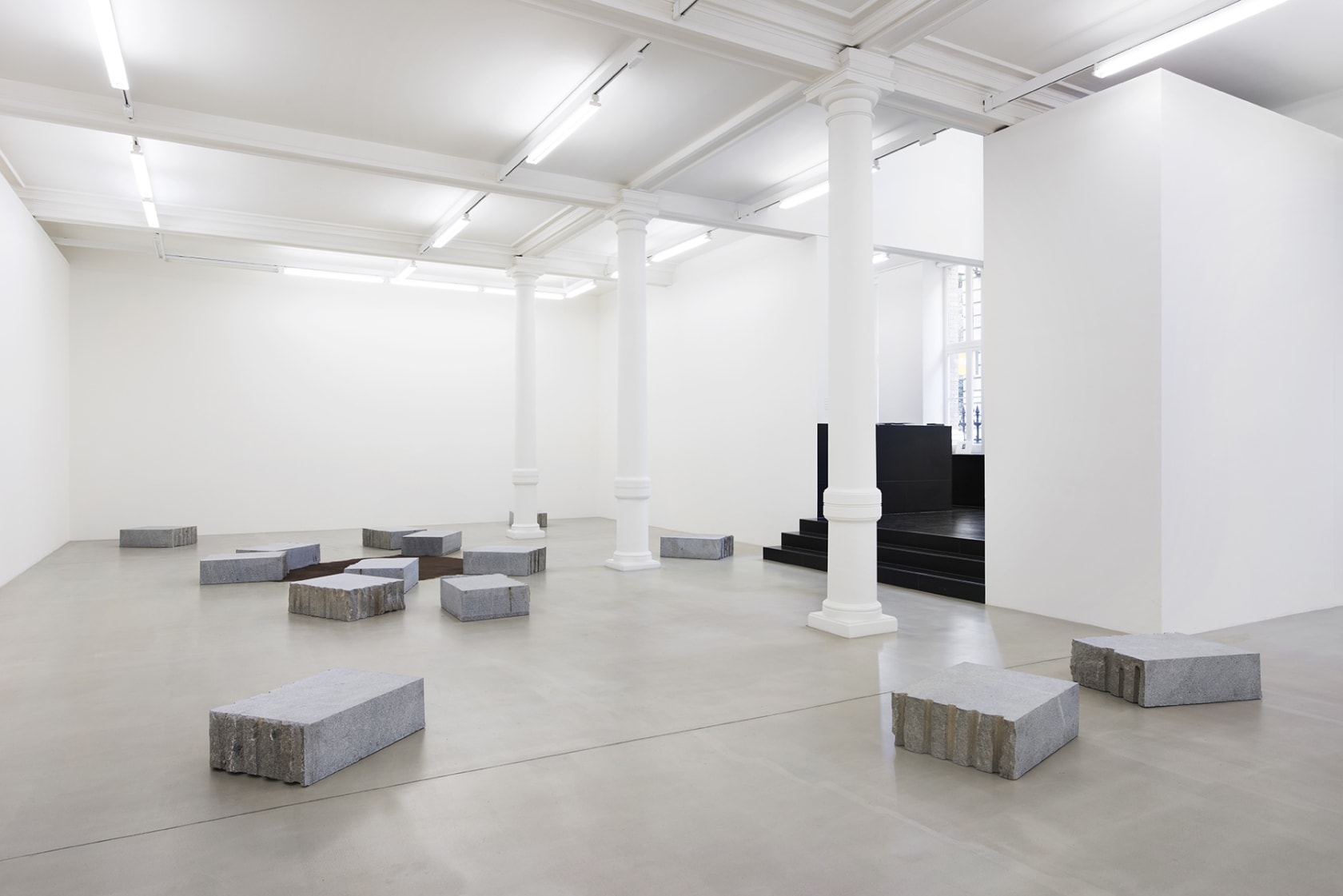 Installation of carved stone blocks around brown suede rug.
