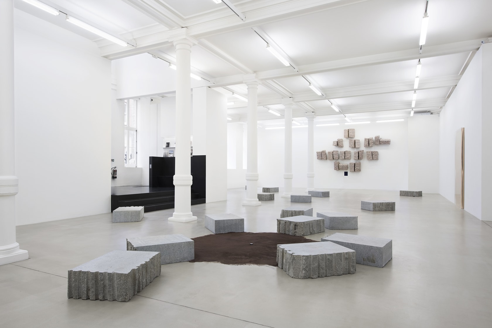 Installation of carved stone blocks around brown suede rug.