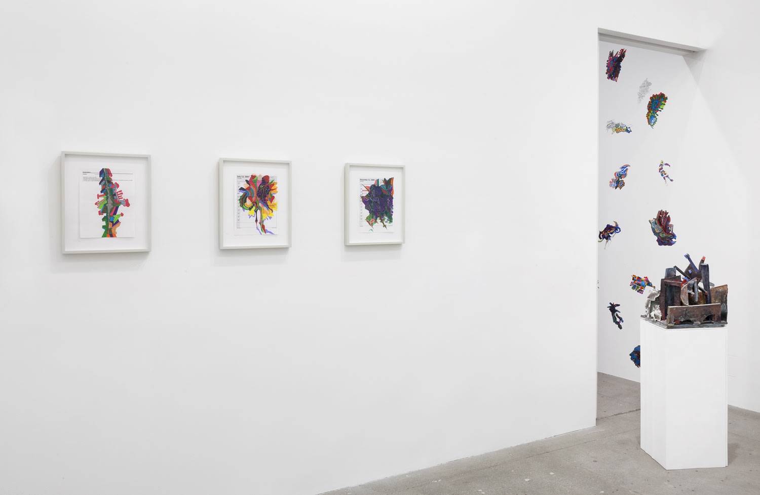 3 framed artworks hang on the wall. To the right is an abstract sculpture and a pattern visible through a doorway.