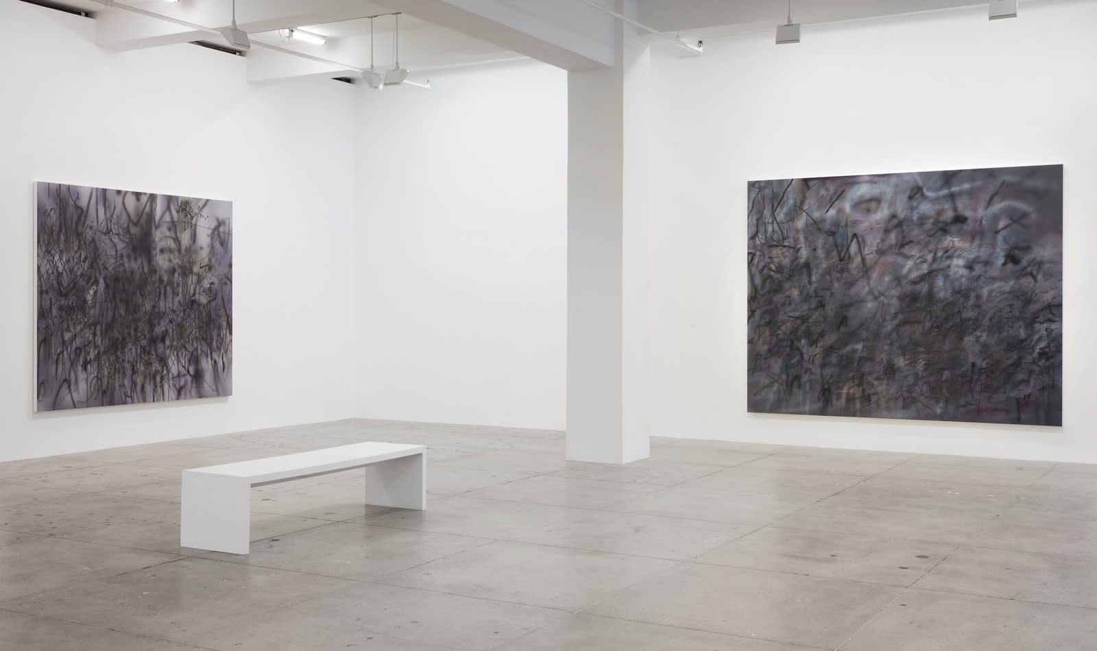 2 abstract paintings hang in a white gallery space with a white bench.