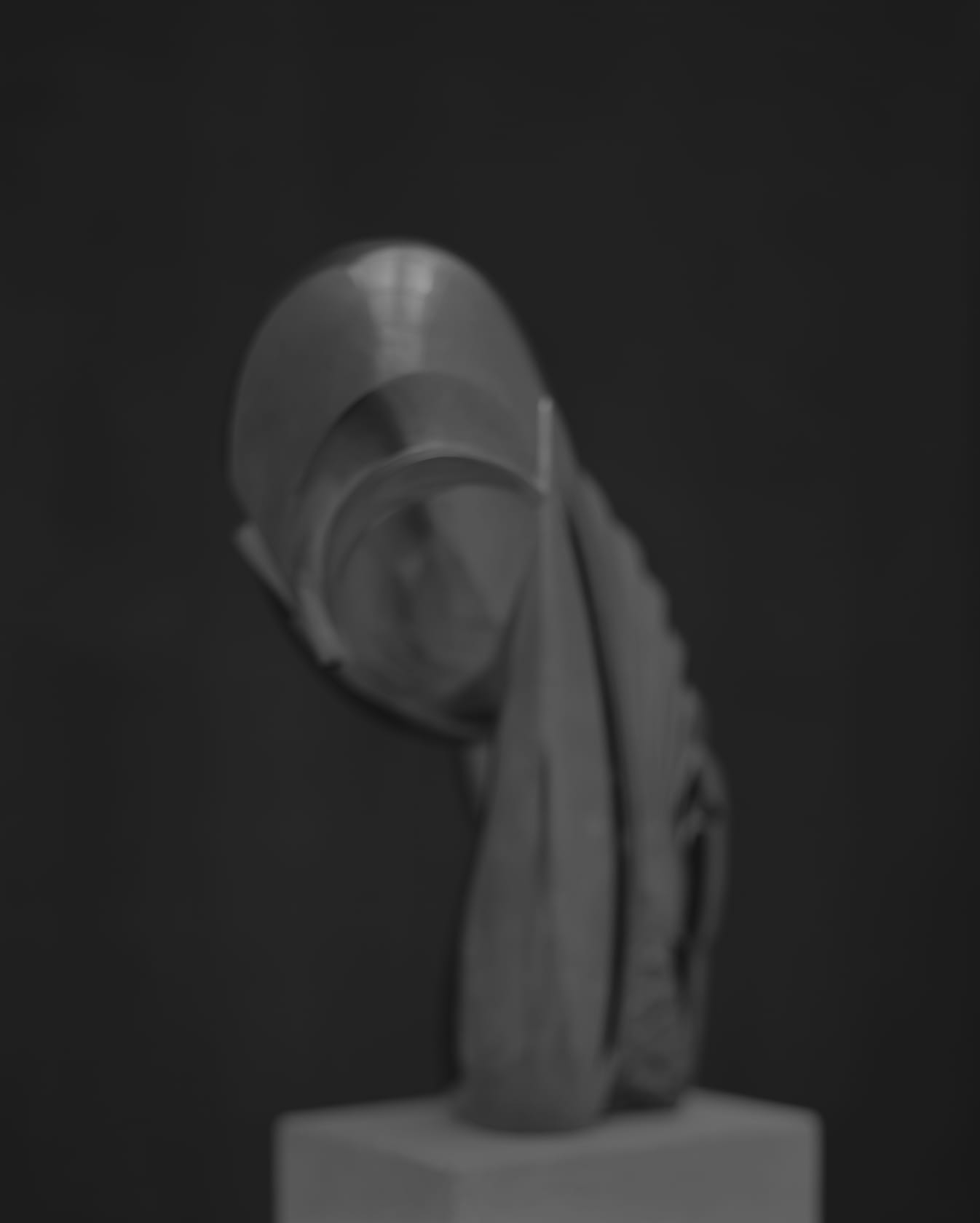 An out of focus, grayscale image of a Brancusi sculpture on a pedestal
