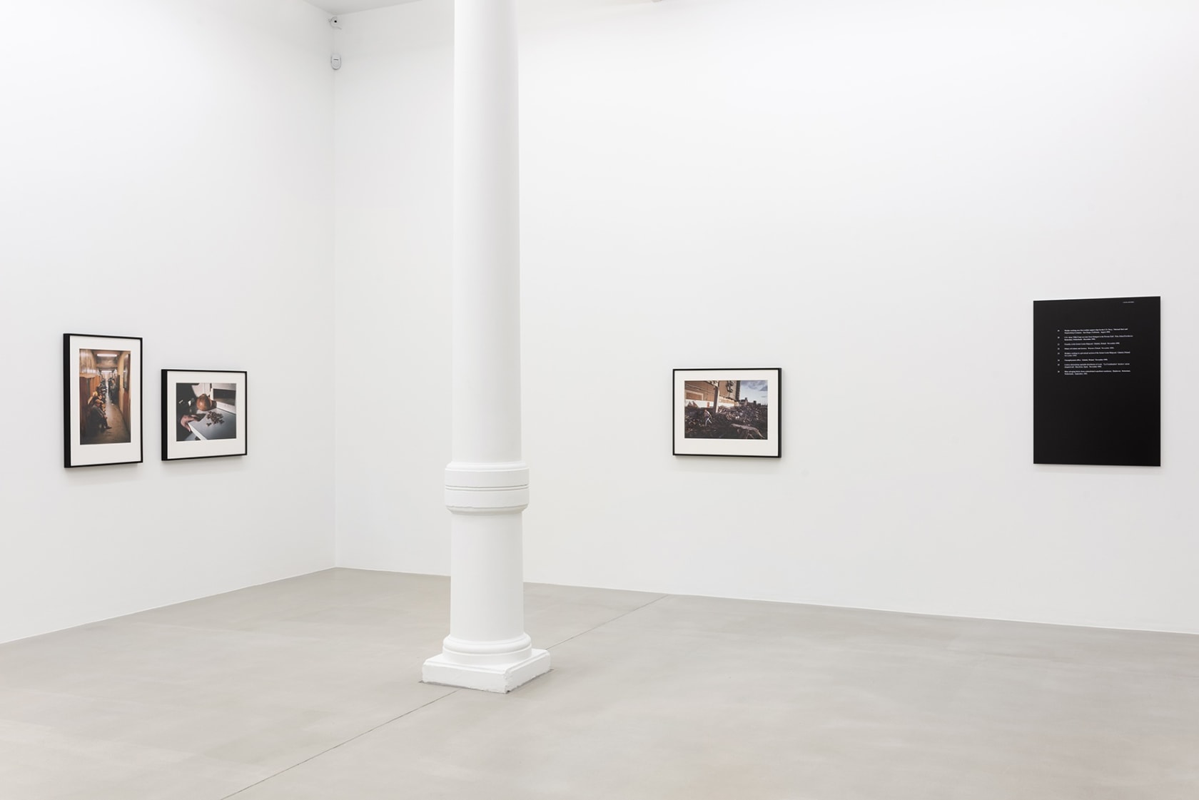 Four small photographs on gallery wall with a pillar between them.