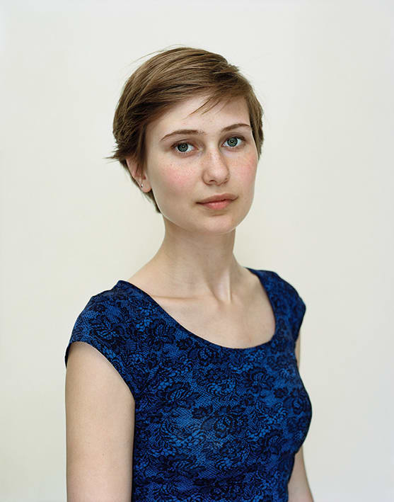 A Rineke Dijkstra portrait of a woman in a blue shirt with short hair.