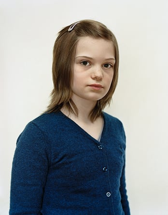 A Rineke Dijkstra portrait of a girl in a blue shirt with short hair.