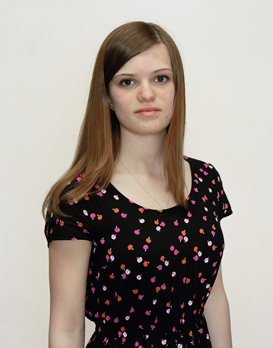 A Rineke Dijkstra portrait of a girl in a black and red floral shirt.