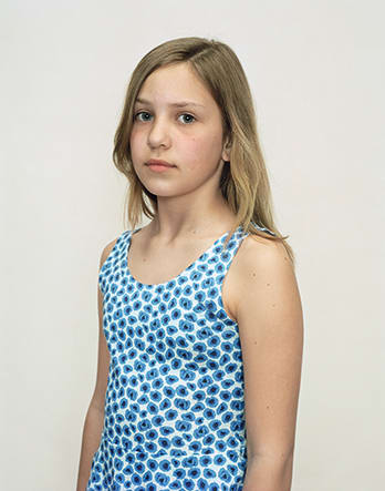 A Rineke Dijkstra portrait of a girl in a blue polka dot tank top.