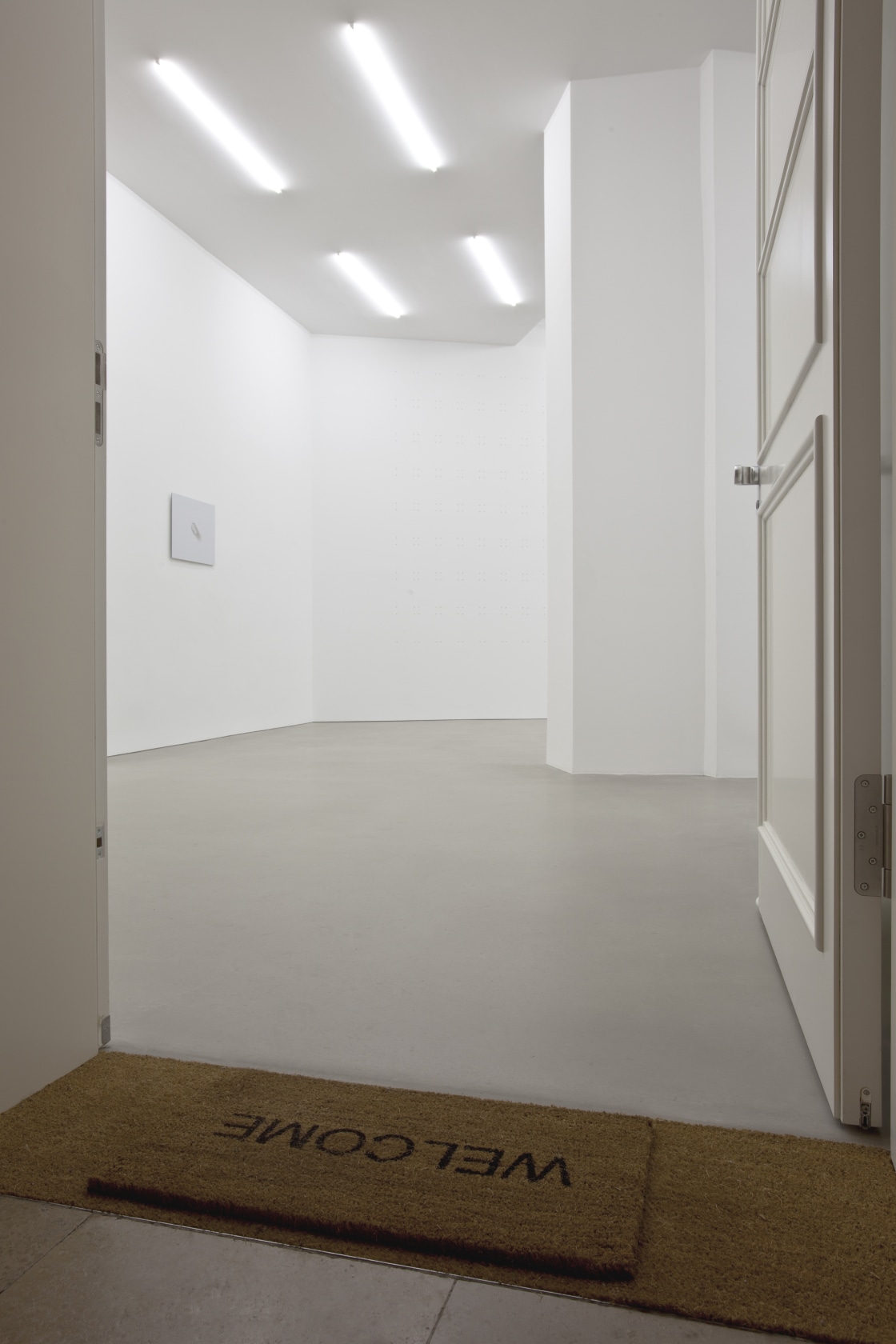 Welcome, 2011 Ready-made welcome mat The ready-made welcome mat is placed at the entrance door to the exhibition space, but...