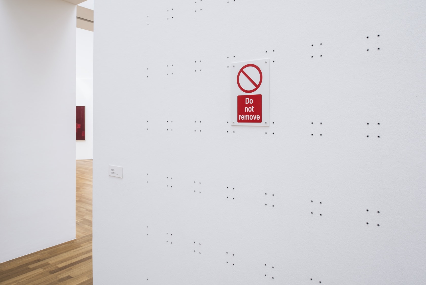 Do Not Remove, 2011 (detail) Wall plugs, ready-made 'Do not Remove' sign, wall Dimensions variable Exhibition view: MENTALES GELB- SONNENHÖCHSTSTAND,...