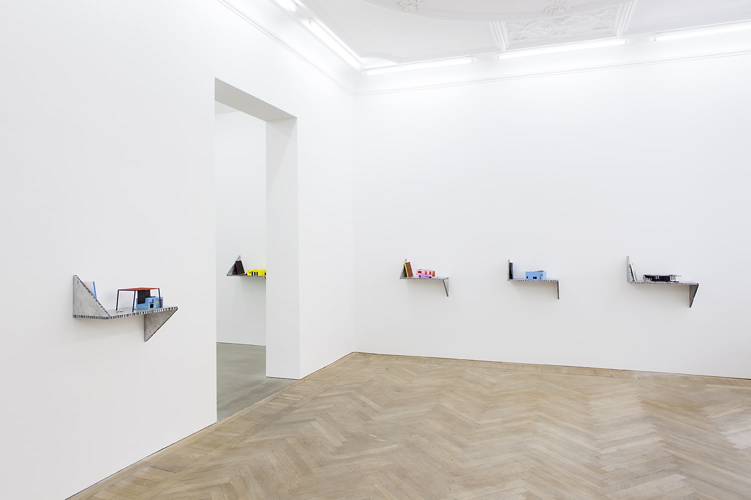 From left to right: Short story house: Over a house, 2014 Painted wood, Stones, leather (house model), offset on paper...