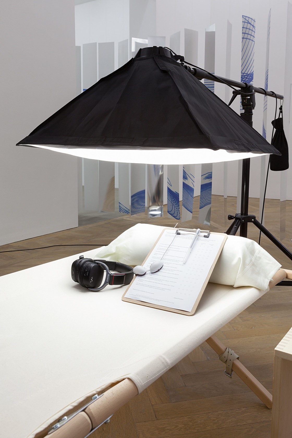 Mental Radio, 2015 (detail, front) Lamp, tripod, cot, pillow, pillowcase, blanket, sidetable, custom-made goggles, wireless MP3 headphones, audio loop, questionnaire,...