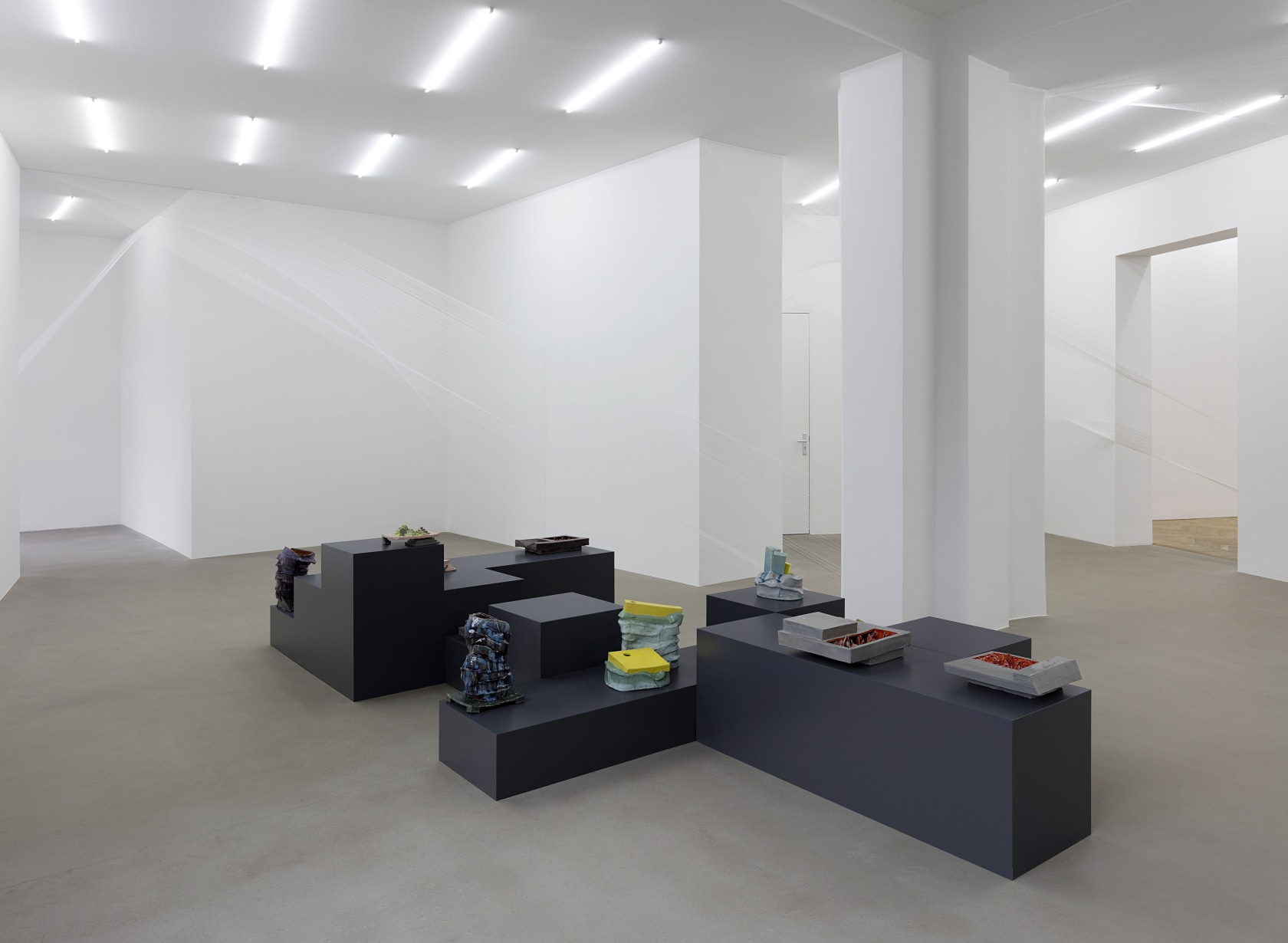 Exhibition view showing ceramic works on custom-made pedestals. In the foreground, in gray and red, works from the series Hausbar,...