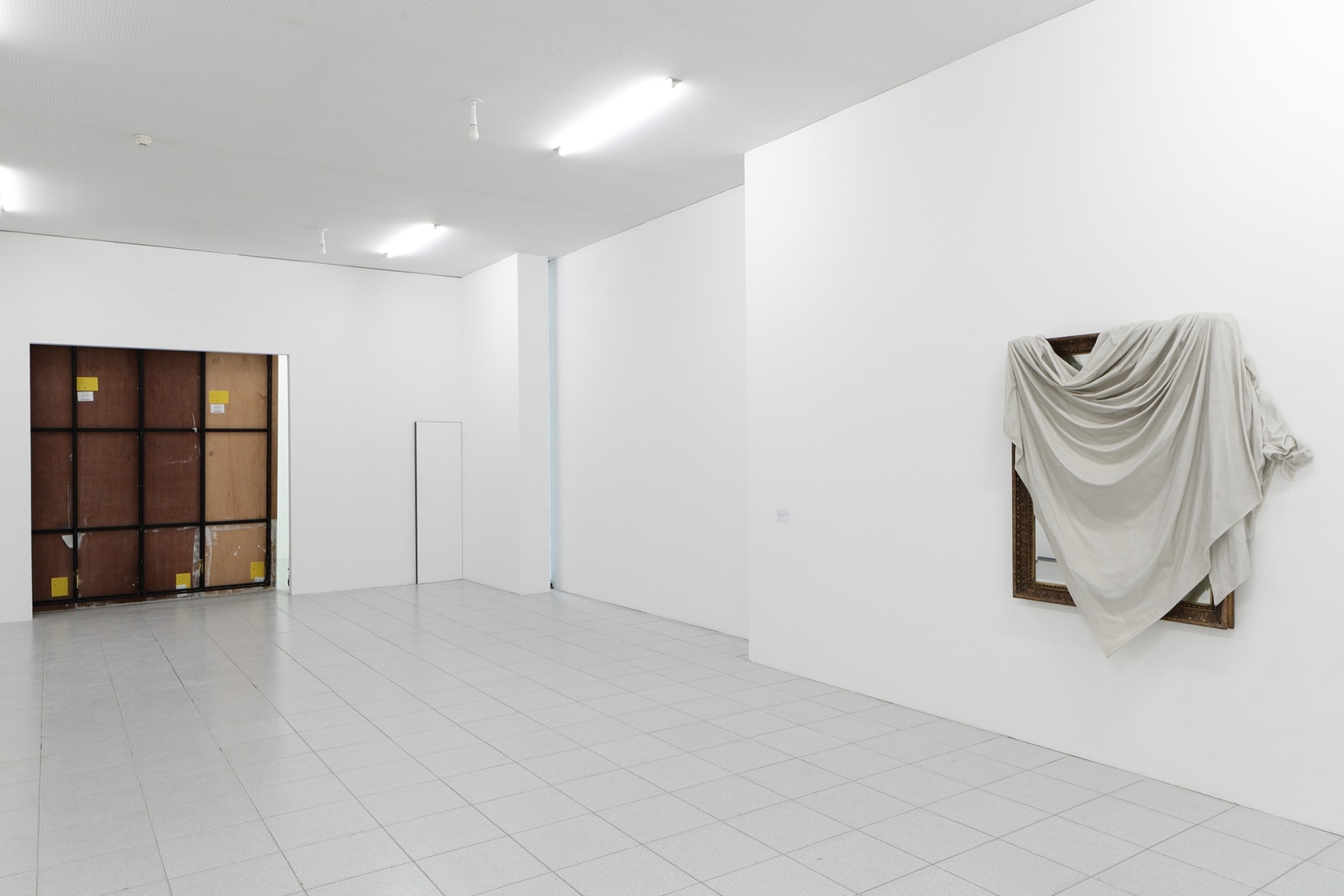 On the right: I be ... (ii), 2015, An existing large framed mirror over which a dust sheet reproduced in...