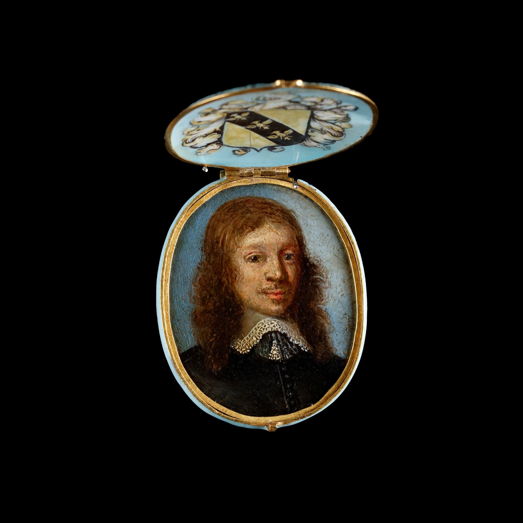 Oil on copper housed in contemporary enamelled gold locket frame, the pale blue base and lid decorated with gilded quatrefoils, the interior of the lid bearing a coat of arms, consisting of a diagonal band of three demi-eagles upon a shield surrounded by acanthus leaves with studded helmet and demi-eagle cresting Oval, 1 7/16 in (36 mm) high