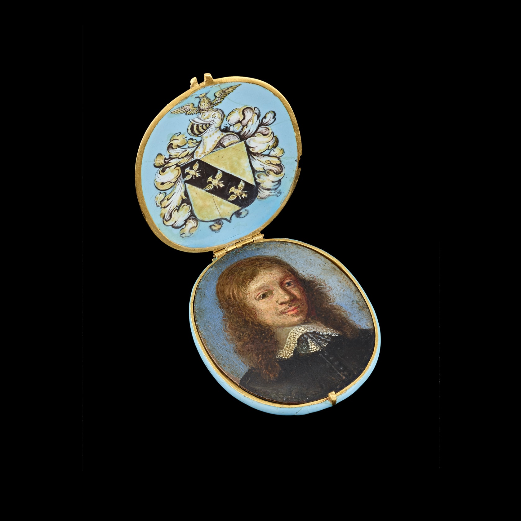 Oil on copper housed in contemporary enamelled gold locket frame, the pale blue base and lid decorated with gilded quatrefoils, the interior of the lid bearing a coat of arms, consisting of a diagonal band of three demi-eagles upon a shield surrounded by acanthus leaves with studded helmet and demi-eagle cresting Oval, 1 7/16 in (36 mm) high